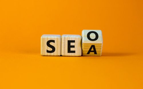 Cubes en bois transformant l'acronyme SEO en SEA, illustrant le choix entre référencement naturel et payant