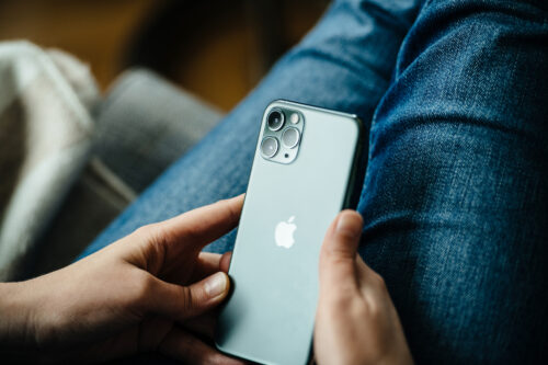 Femme utilisant un iPhone 11 Pro dont l'écran affiche une teinte verte inhabituelle