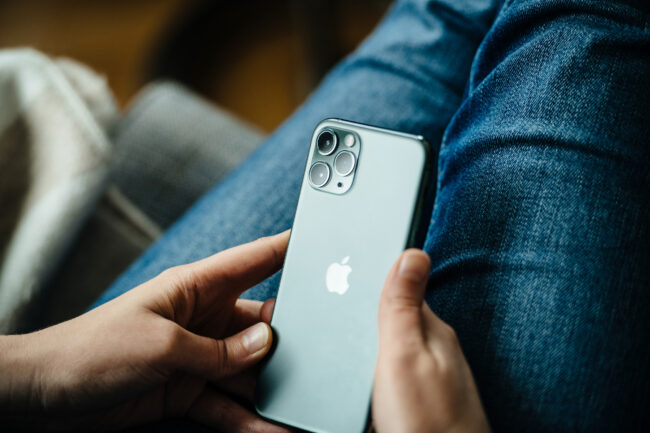 Femme utilisant un iPhone 11 Pro dont l'écran affiche une teinte verte inhabituelle