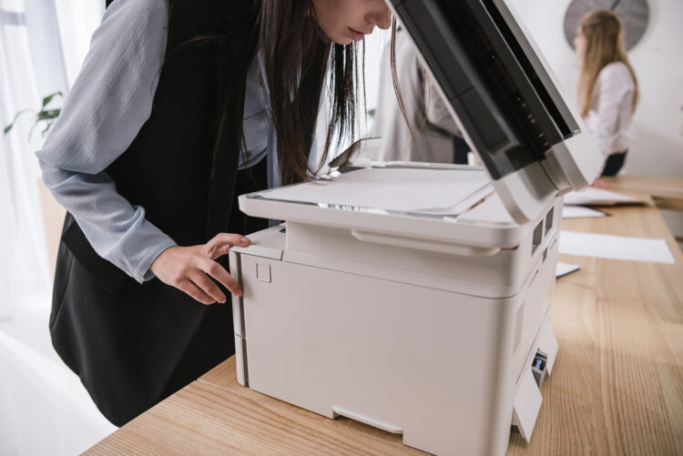 Une femme en train de numériser un document via une imprimante multifonction