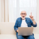 Senior souriant utilisant un ordinateur portable en sécurité à la maison