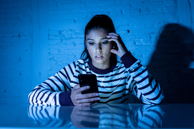 Jeune femme inquiète devant son smartphone après un appel de démarchage insistant