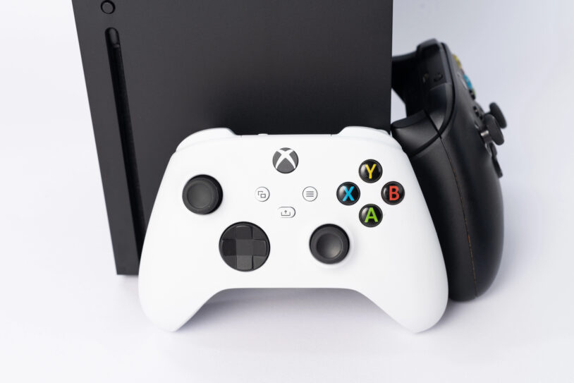 Console Xbox Series X noire avec une manette blanche et une manette noire, modèle touché par la hausse des prix