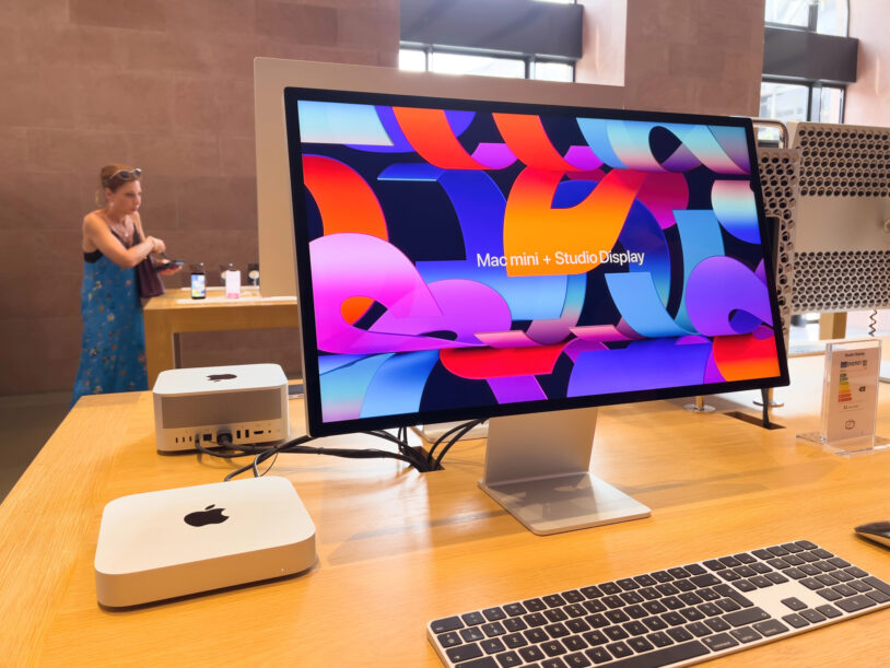Mac mini et Mac Studio exposés en Apple Store à côté d'un Studio Display, sur une table de démonstration