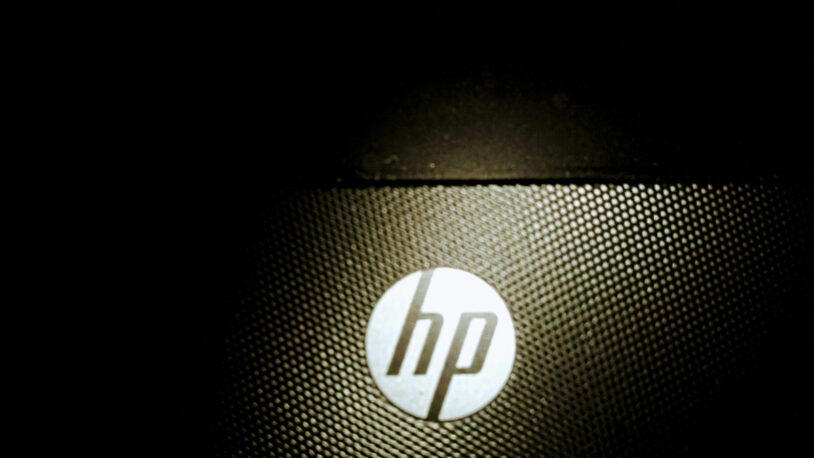 Logo HP sur la grille d'aération d'un ordinateur, éclairé dans la pénombre