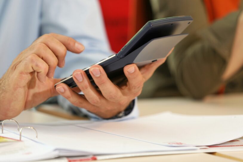 Mains tenant une calculatrice au-dessus de documents pour estimer le financement d'une formation en reconversion